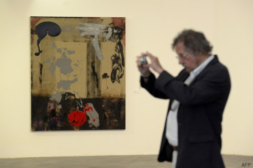 A man takes a photo next to an artwork at a retrospective of US actor Sylvester Stallone's  paintings entitled "Real Love" Paintings 1975-2015 at the Museum of Contemporary Art in Nice, southeastern France, on May 16, 2015.  AFP PHOTO / FRANCK PENNANT = RESTRICTED TO EDITORIAL USE, MANDATORY MENTION OF THE ARTIST UPON PUBLICATION, TO ILLUSTRATE THE EVENT AS SPECIFIED IN THE CAPTION =